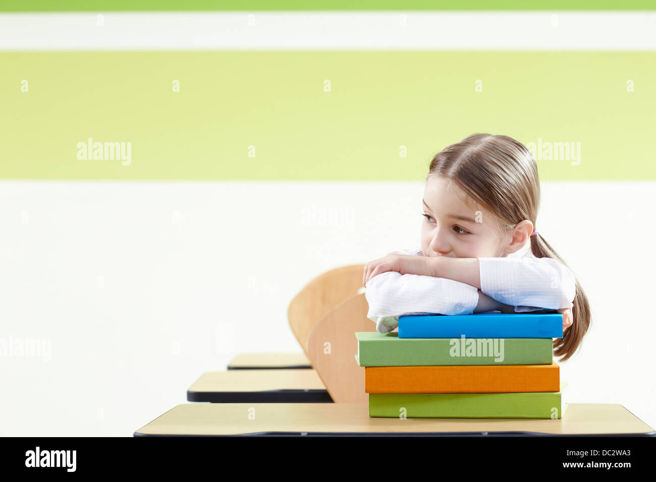a girl leaning on a pile of books in a classroom Stock Photo - Alamy