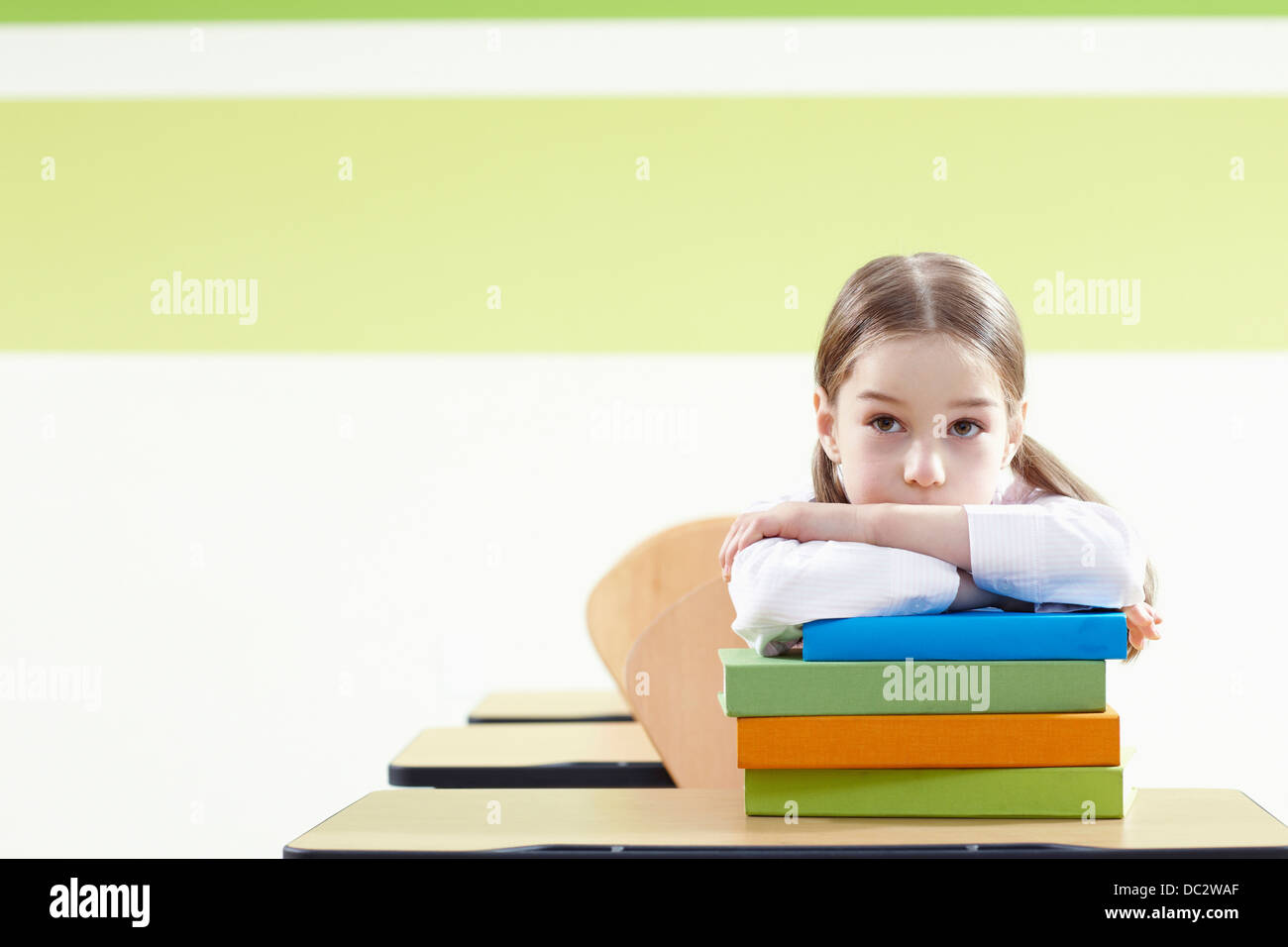 a girl leaning on a pile of books in a classroom Stock Photo - Alamy