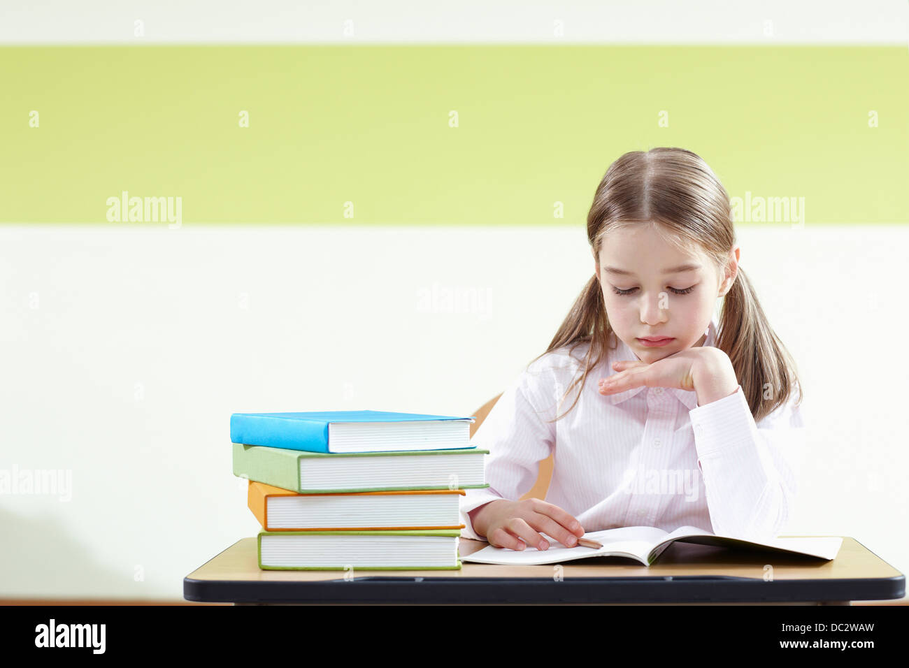 a girl sitting at a desk in a classroom studying Stock Photo - Alamy