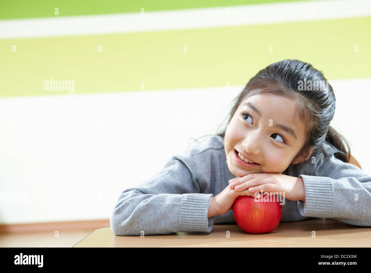 a girl with an apple in a classroom Stock Photo - Alamy