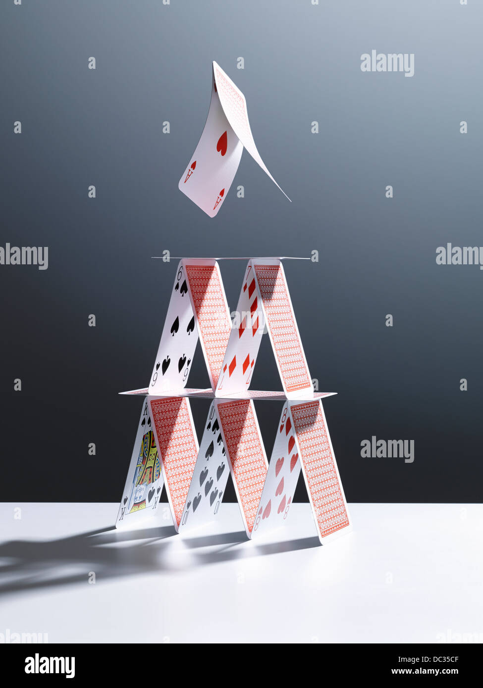 Cards jumping above house of cards Stock Photo