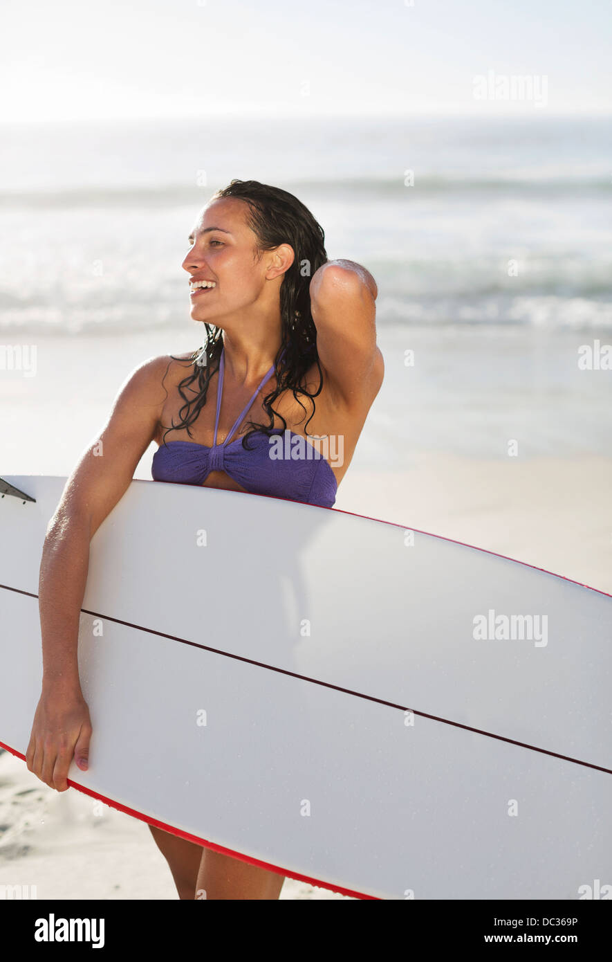 Smiling woman holding surfboard on beach Stock Photo - Alamy