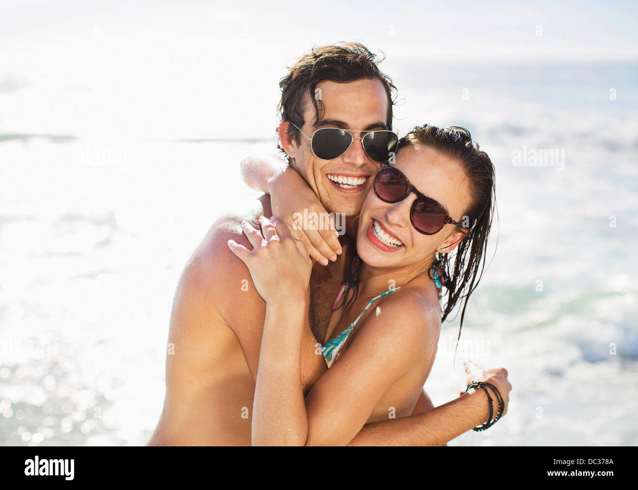 Portrait of enthusiastic couple in sunglasses hugging on beach Stock Photo