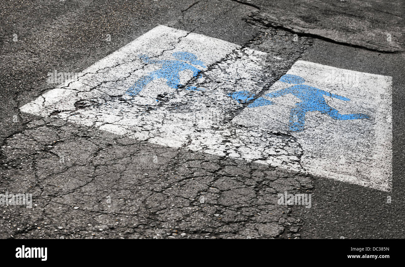 Warning road sign with blue running children on old asphalt Stock Photo