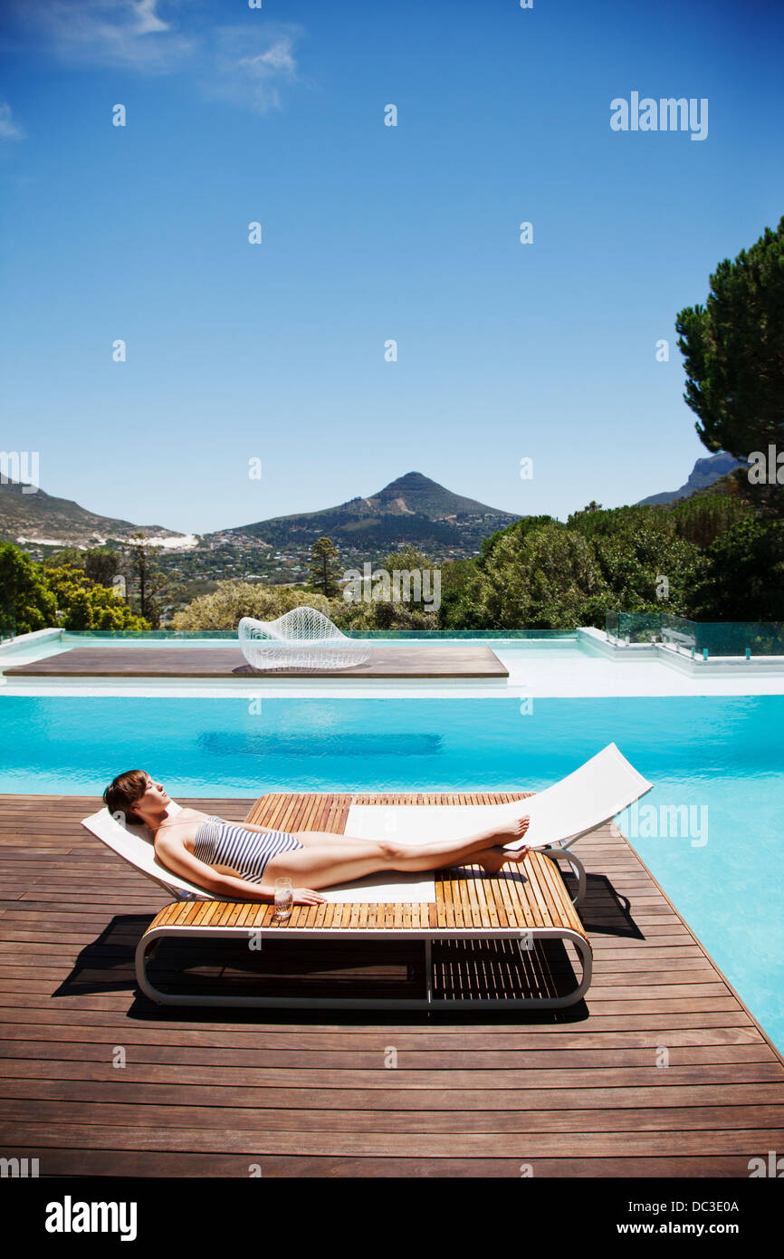 Woman sunbathing at poolside Stock Photo