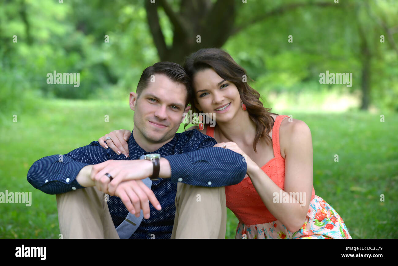 Portrait of young happy couple in love, smiling and embracing in garden.  Sweet lovers wearing in