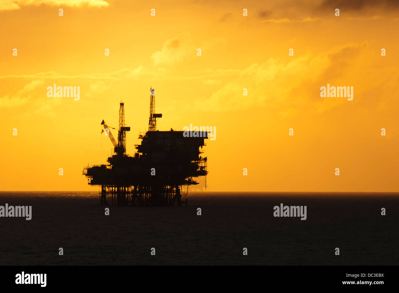 Silhouette of an offshore oil rig far on the horizon at sunset/sunrise time. Stock Photo