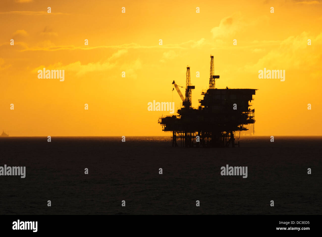 Silhouette of an offshore oil rig far on the horizon at sunset/sunrise time. Stock Photo