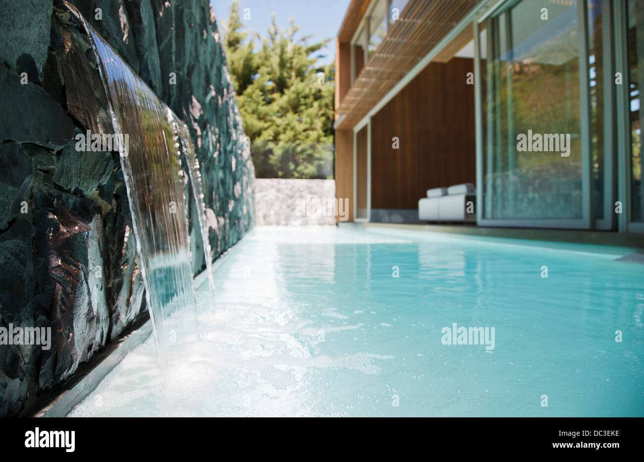 Waterfall emptying into pool of modern house Stock Photo