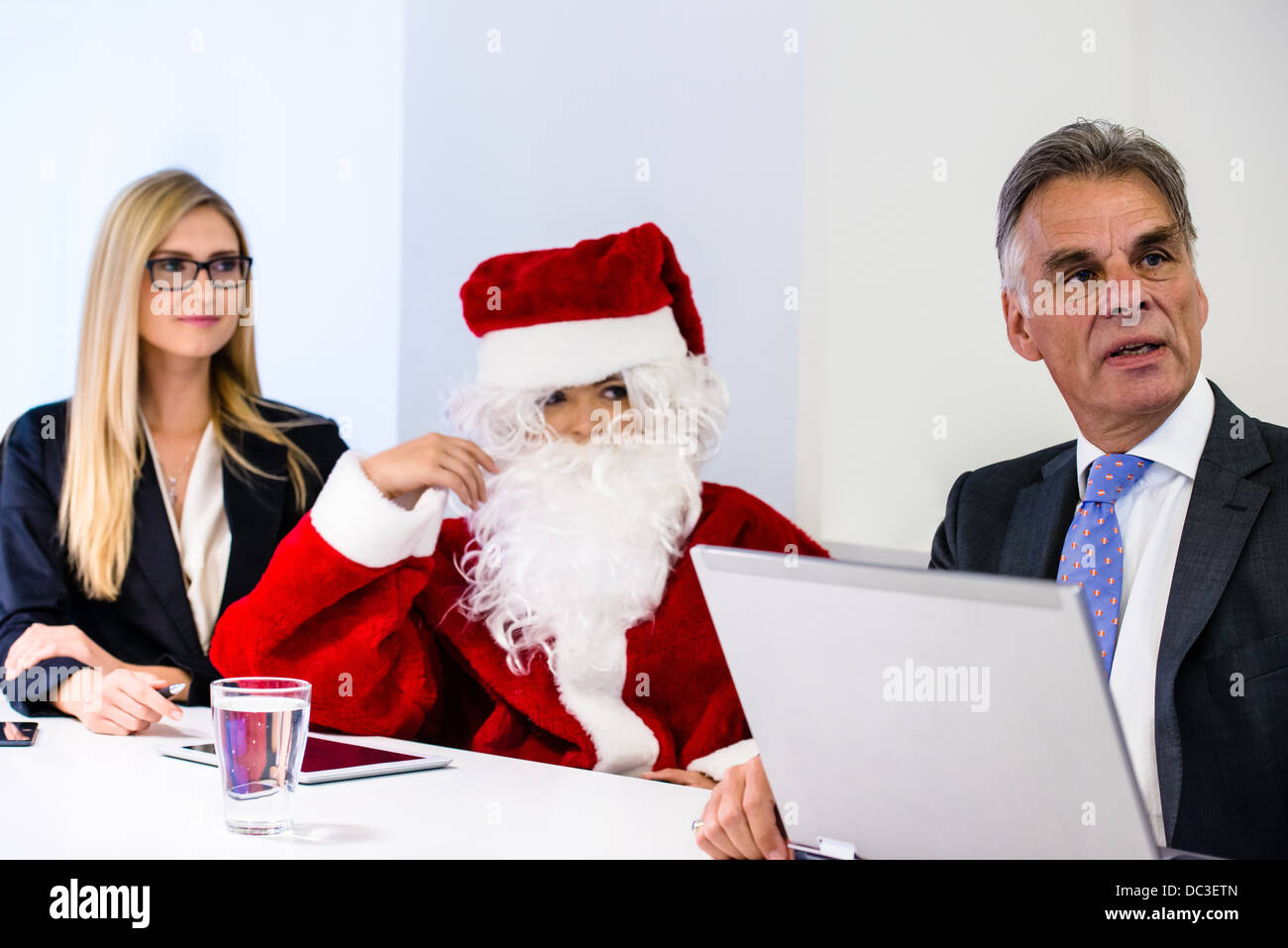 Santa Claus particpating in business meeting with laptop, digital tablet and smartphones discussing the latest figures Stock Photo