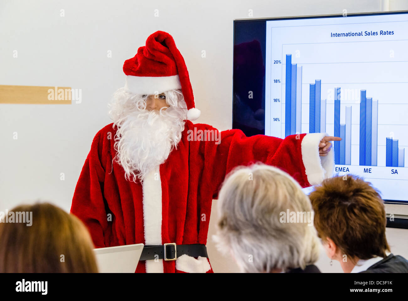 Female Santa Claus in business meeting presenting the latest sales figures Stock Photo