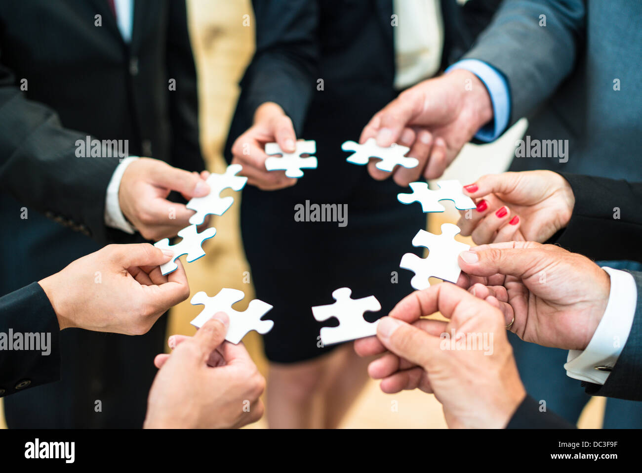 Teamwork - a group of eight business people assembling a jigsaw puzzle - representing team support and help concepts Stock Photo