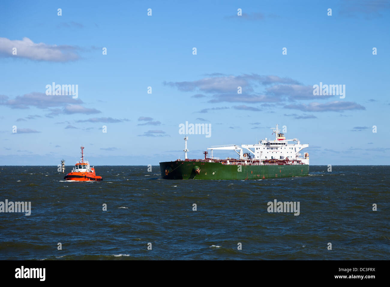 A huge oil tanker and a tugboat at work. Stock Photo