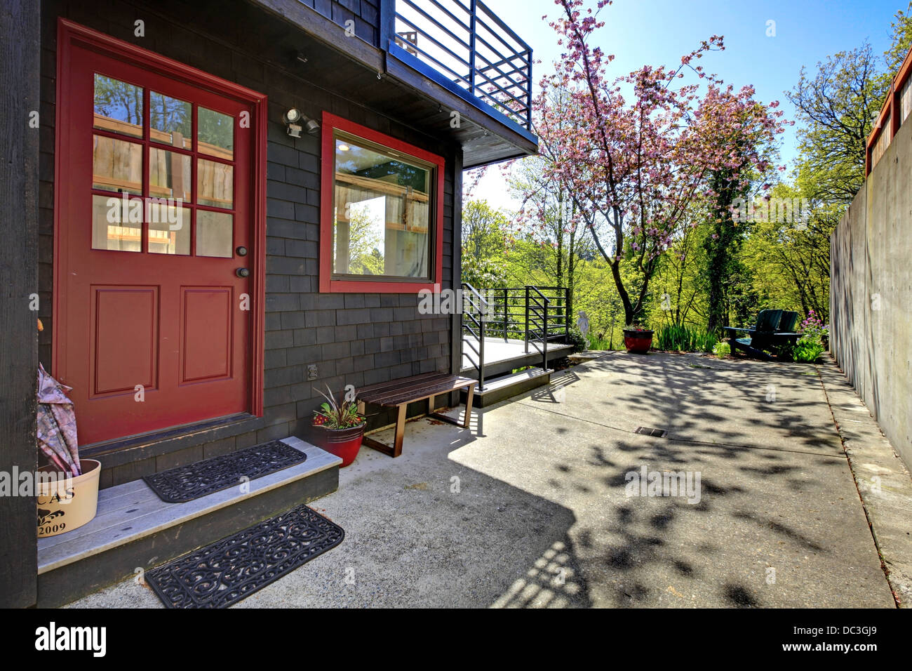 Front red door of black wood house with garden view. Stock Photo