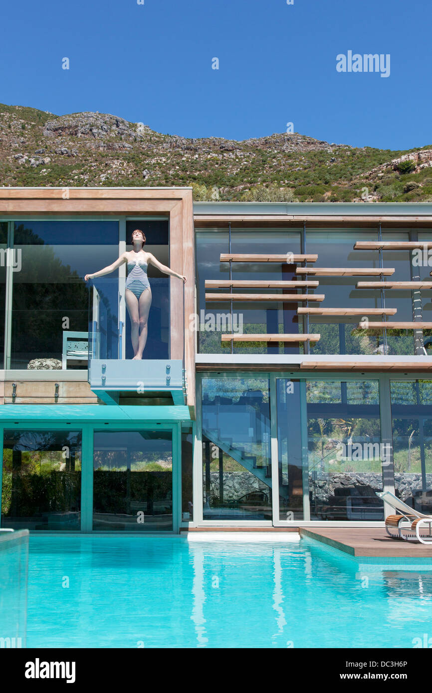 Woman on balcony above swimming pool Stock Photo