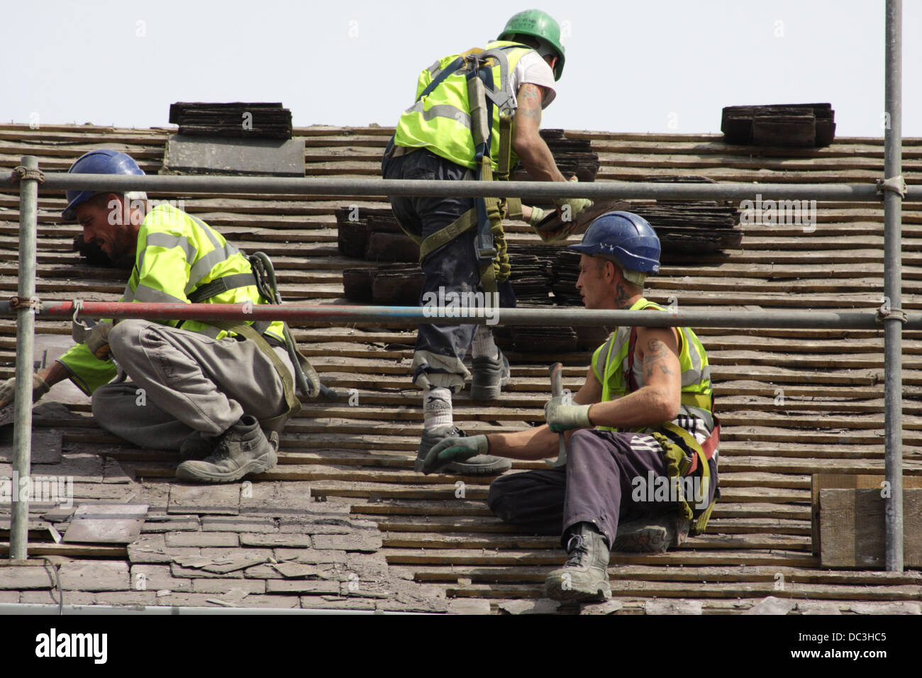 Workmen removing old roof tiles, prior to demolition of the properties. Stock Photo