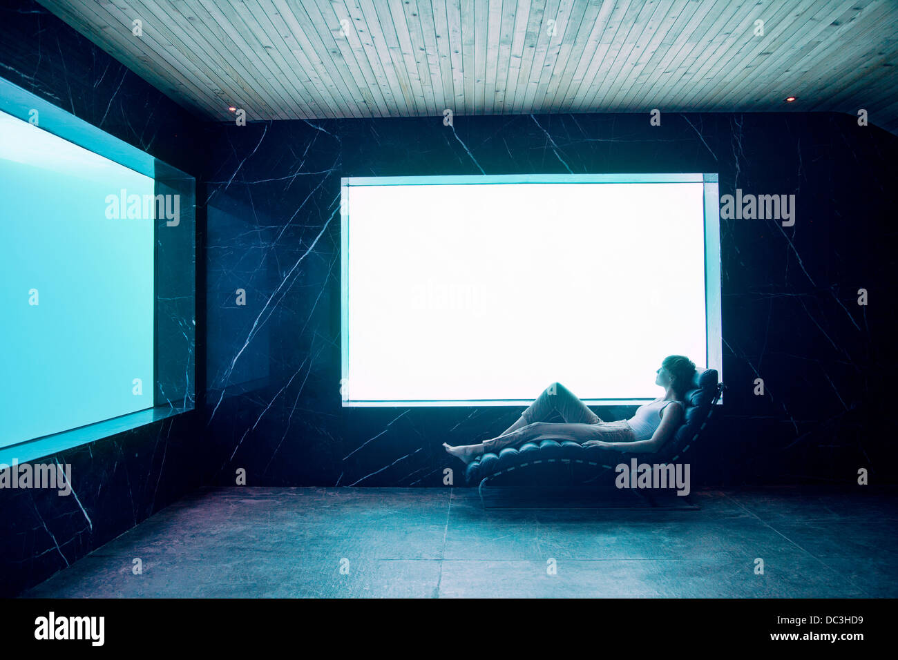Woman in lounge chair in pool room Stock Photo