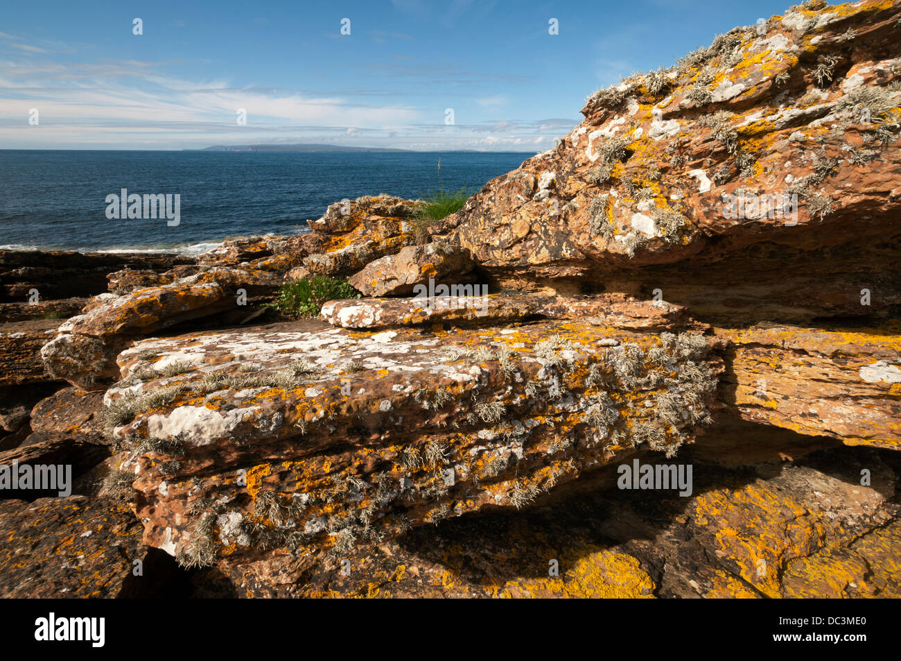 Hoy (Orkney) over the Pentland Firth from near village of Mey, Caithness, Scotland, UK.  Lichen covered rocks in the foreground. Stock Photo