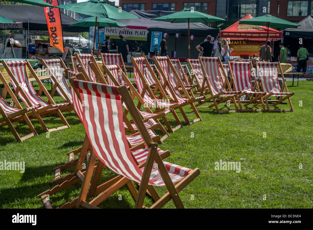Red and white deck chairs on grass in a semi circle hires stock