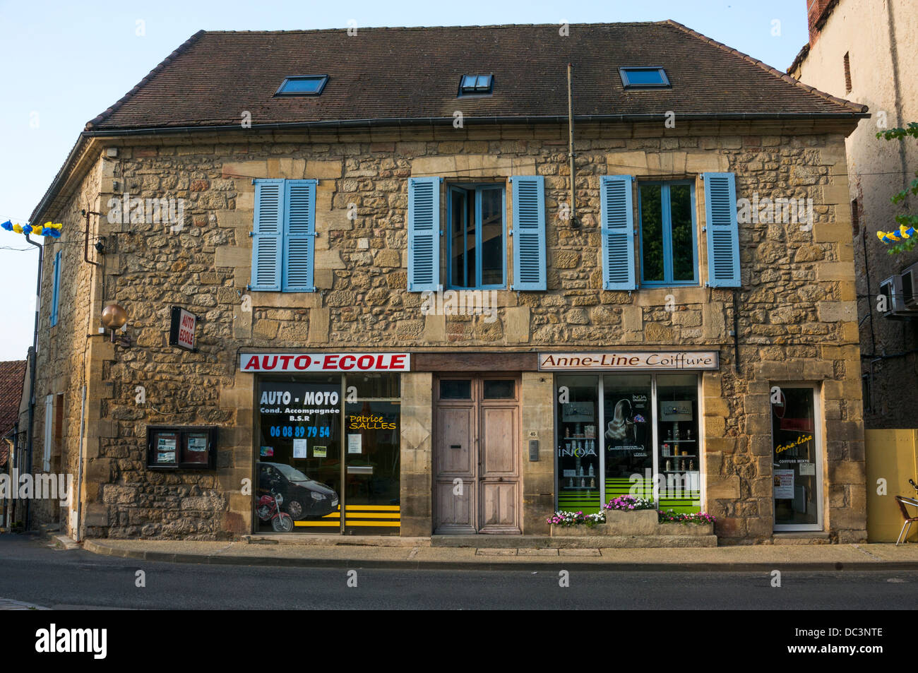 A shared driving school and hairdresser, traditional building in Saint-Cyprien, in the Dordogne, Aquitaine, south west France. Stock Photo