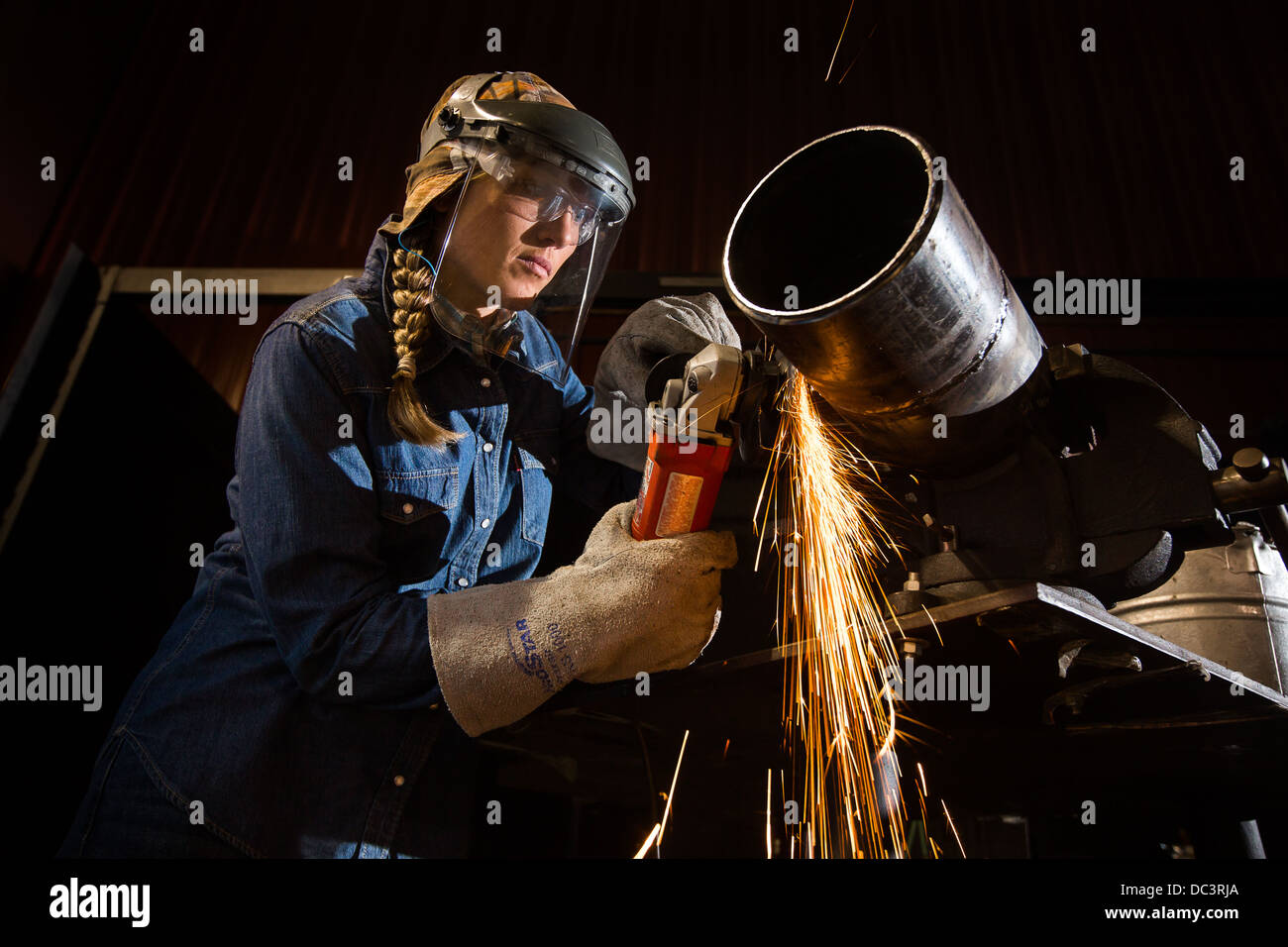 Female welder watches sparks. Stock Photo