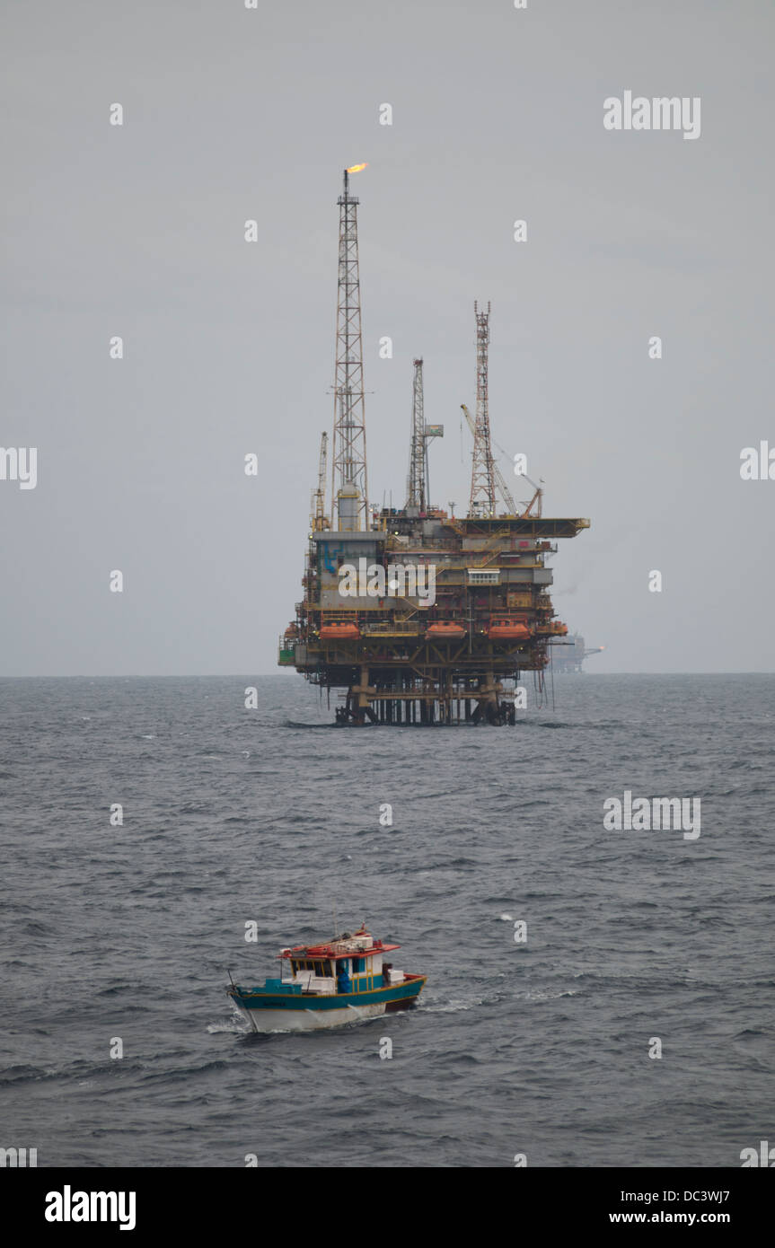 Fishing boat close to offshore oil rig PGP-1 at Campos basin, Rio de Janeiro.  Rig working for Petrobras oil company. Stock Photo