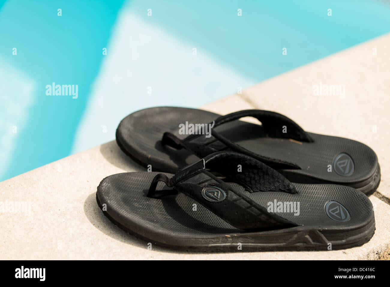Pair of black flip flops next to swimming pool Stock Photo Alamy