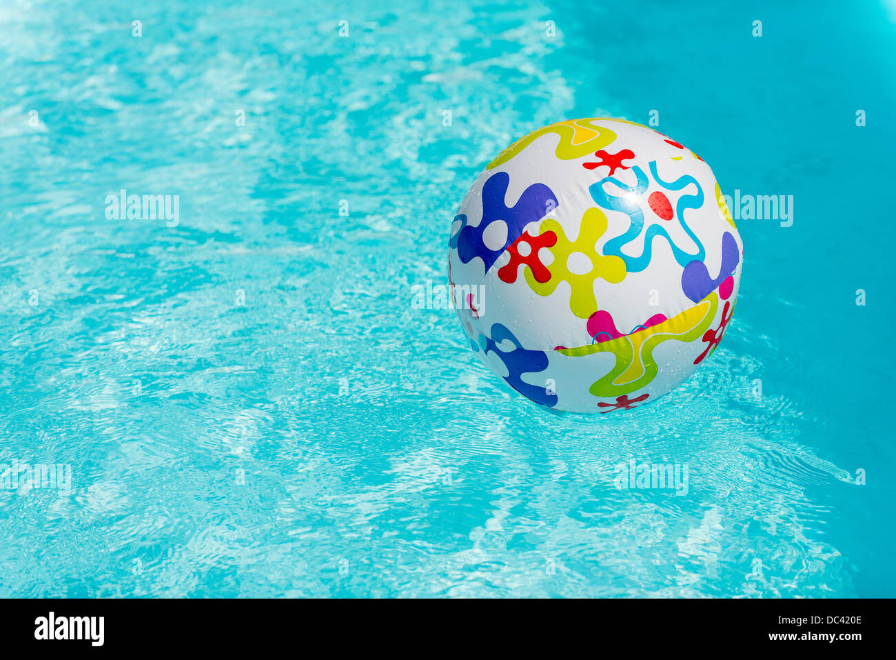 Colorful beach ball floating on water of swimming pool Stock Photo