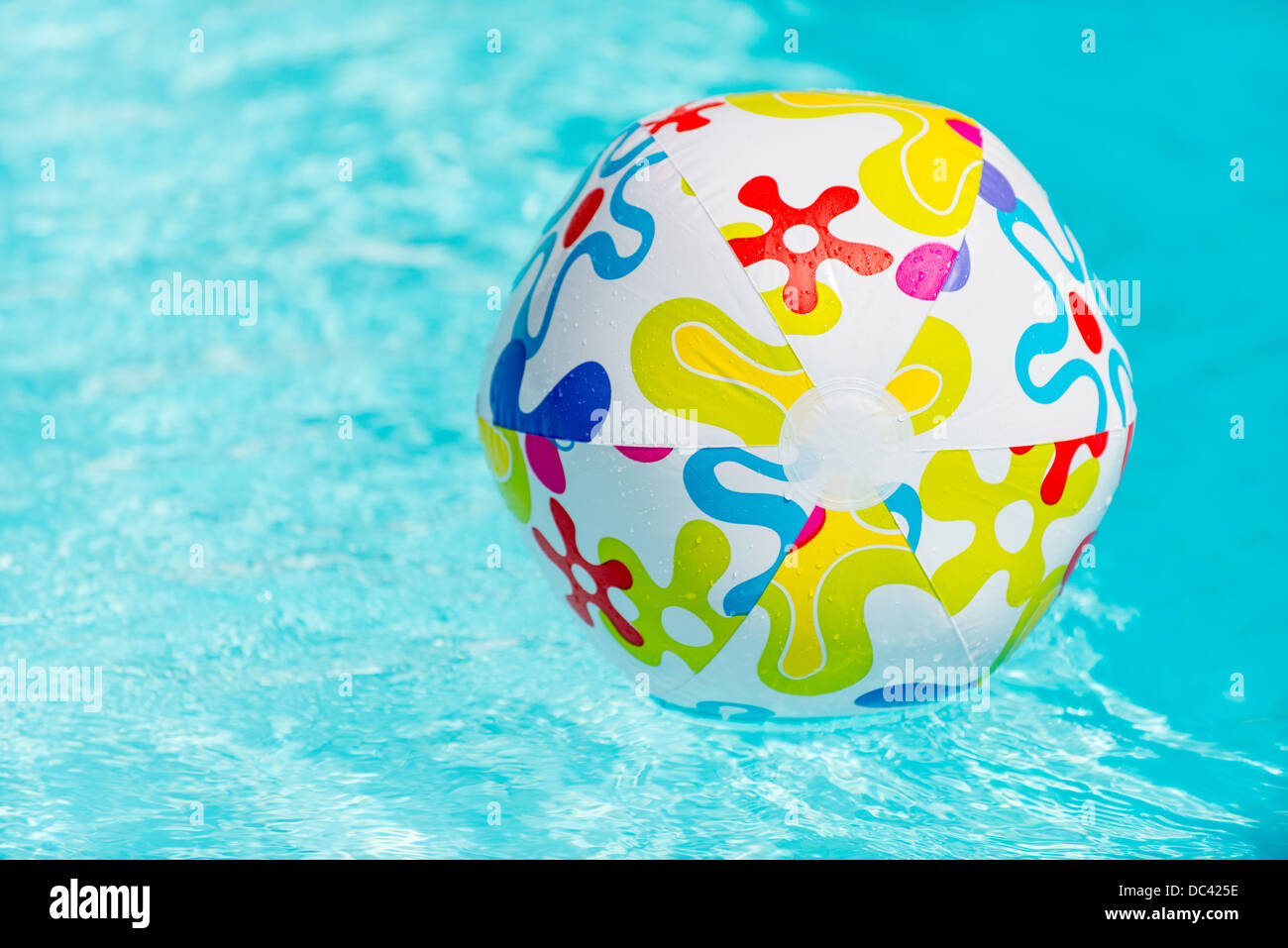 Colorful beach ball floating on water of swimming pool Stock Photo