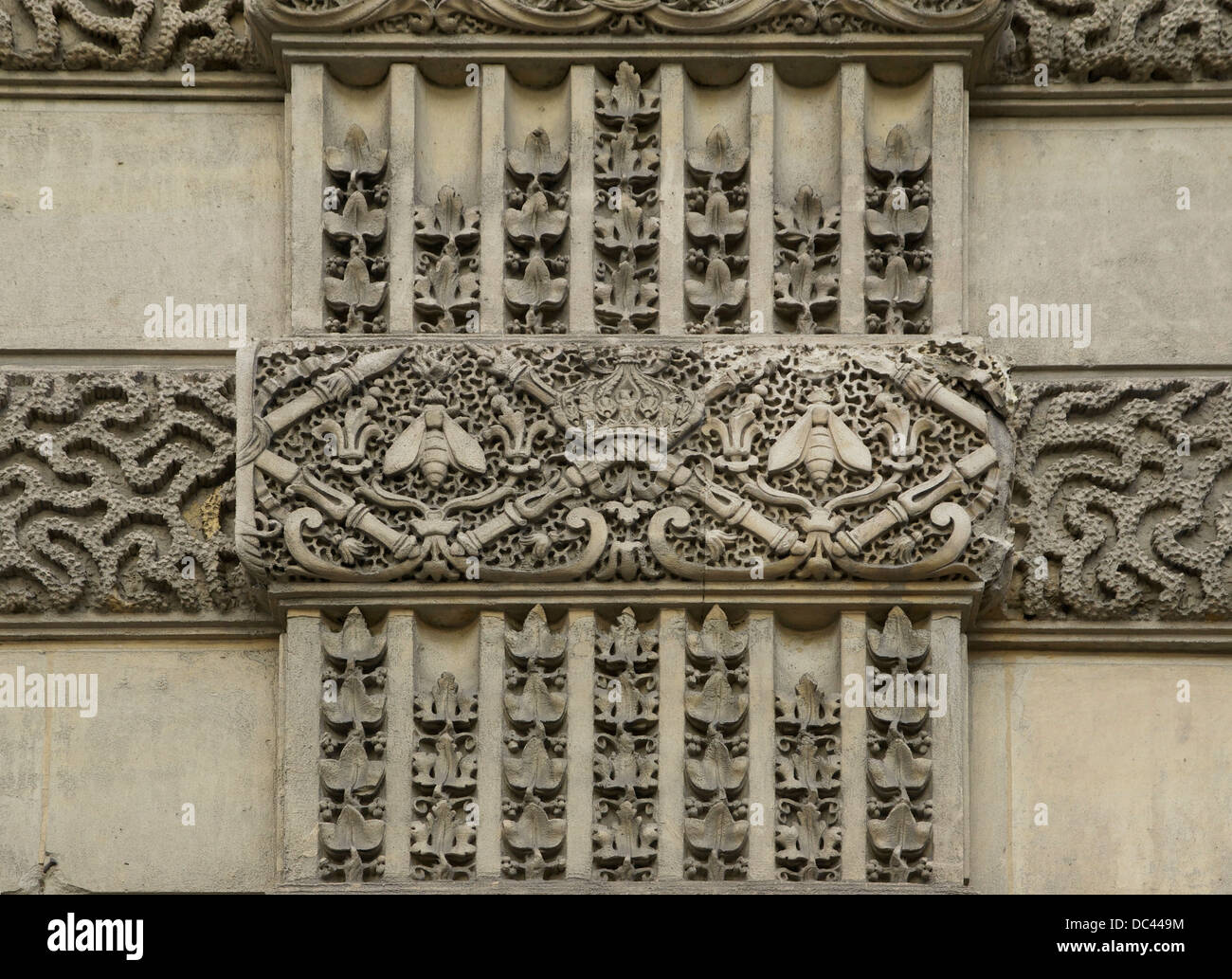 Details of sculpted decorations visibles on the walls of the Louvre Palace in Paris. One can see an imperial crown, sceptres, an Stock Photo