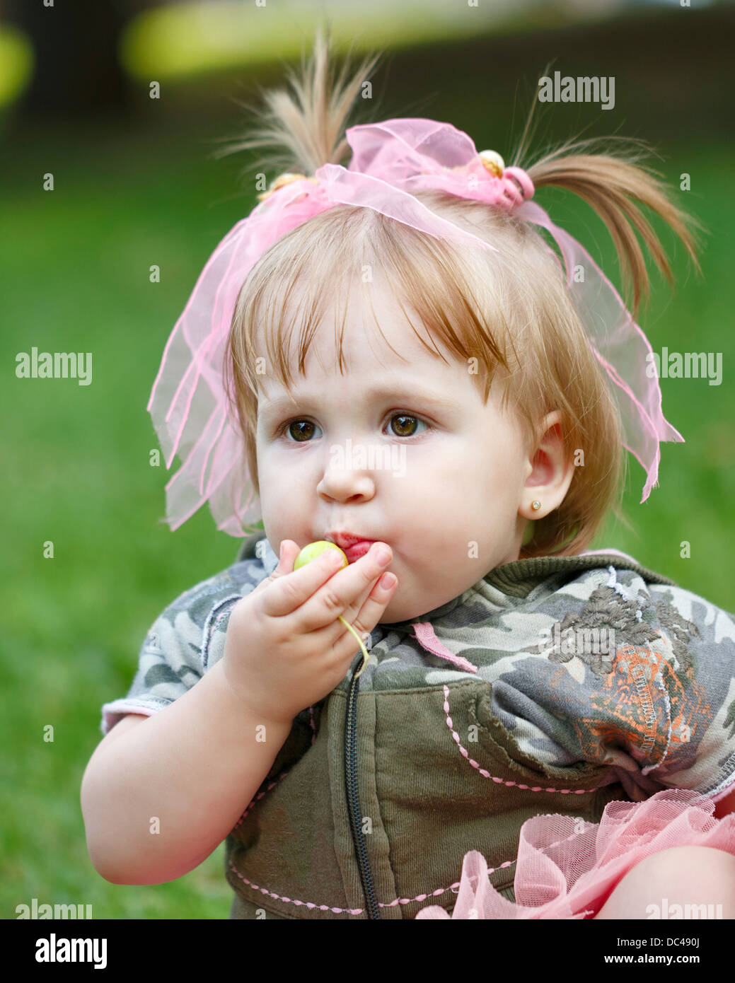 Little blond girl in a blue skirt eating an apple Stock Photo Alamy