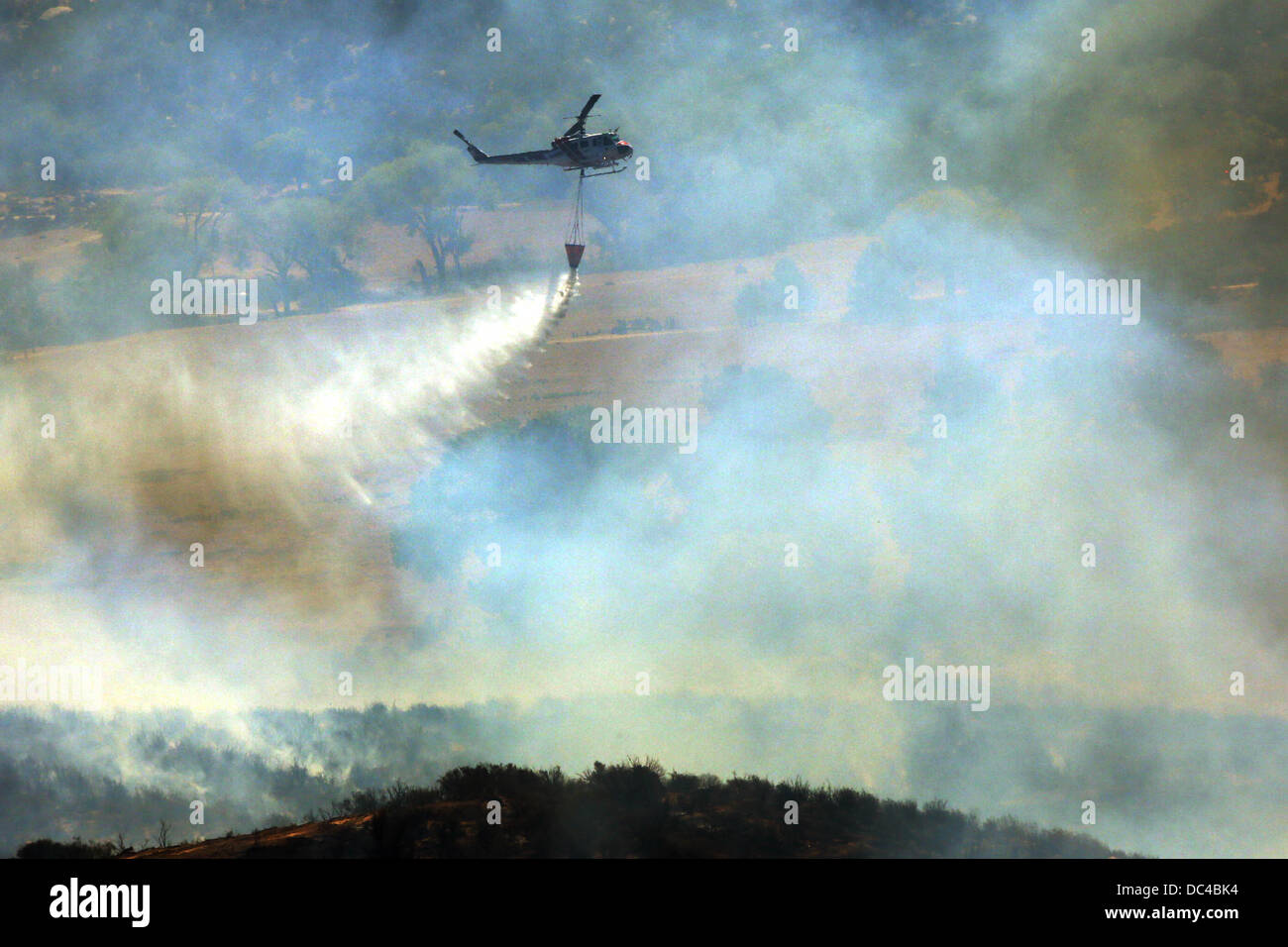 Banning, CA, USA. 8th Aug, 2013. Helicopters make water drops on active flames in a valley near Banning. The explosive Silver fire in Riverside County was 10% contained Thursday as it moved east toward the desert, having already scorched 11,000 acres and destroyed homes and other structures. One local resident was severely injured overnight, and four firefighters were also injured. The fire was burning in an area that has not burned for about seven years since the Esperanza Fire in 2006. Credit:  Krista Kennell/ZUMAPRESS.com/Alamy Live News Stock Photo