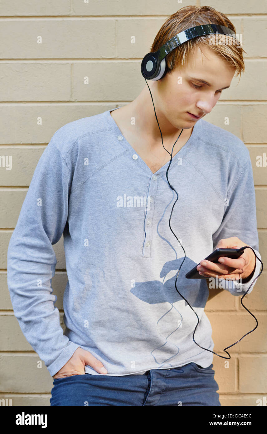 Young male scrolling through song list with sun highlighting mp3 player Stock Photo