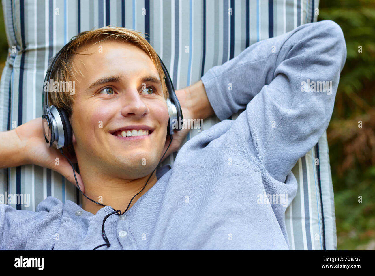 Young good looking male relaxing and listening to music with headphones. Stock Photo