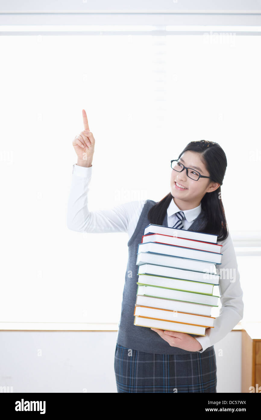 student in school uniform holding a pile of books Stock Photo - Alamy
