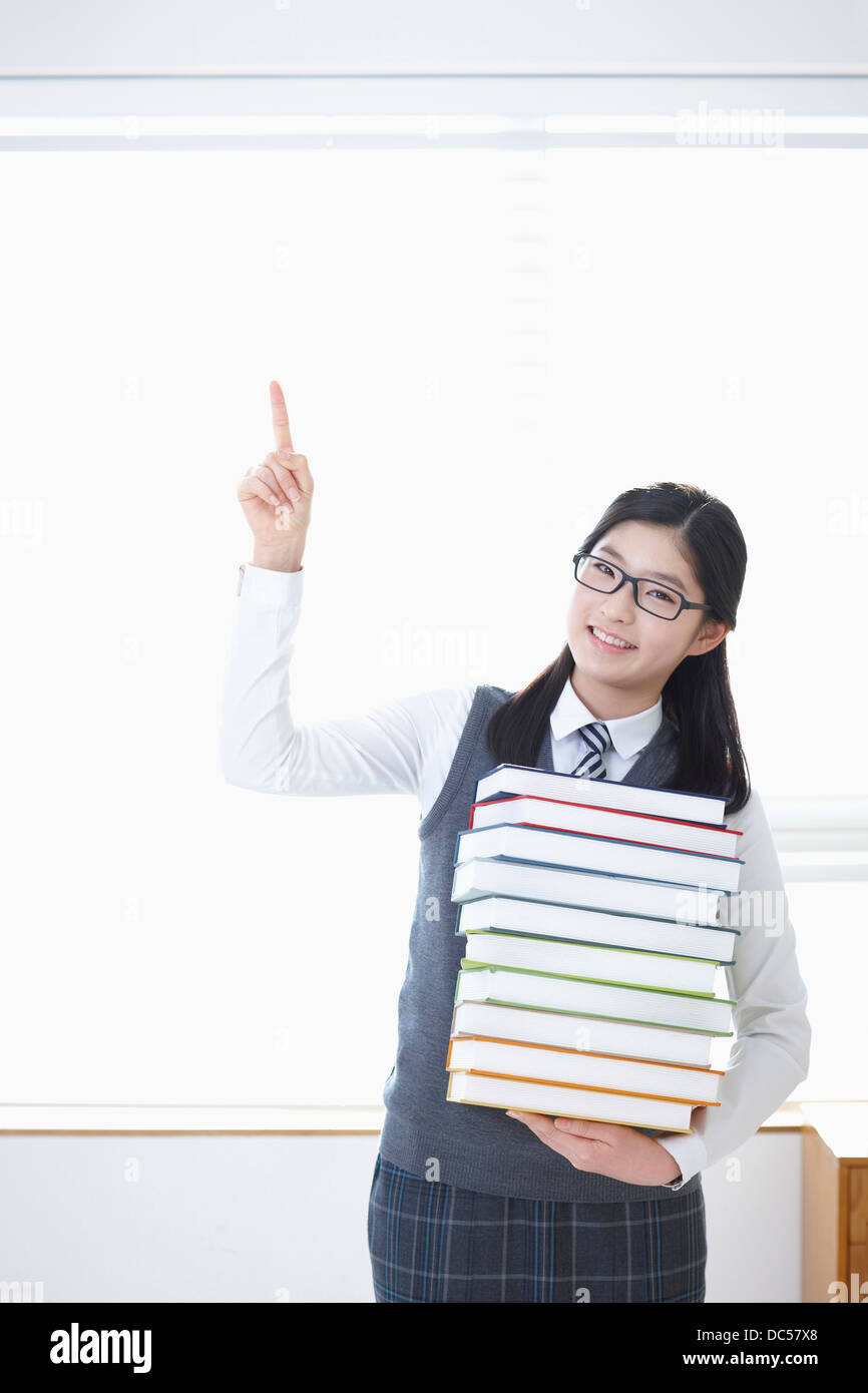 student in school uniform holding a pile of books Stock Photo - Alamy