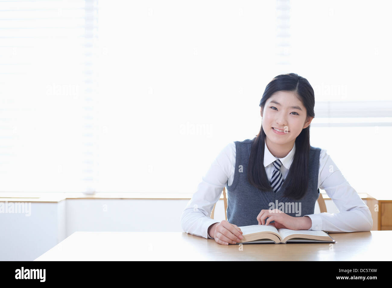 student in school uniform reading a book sitting at desk Stock Photo ...