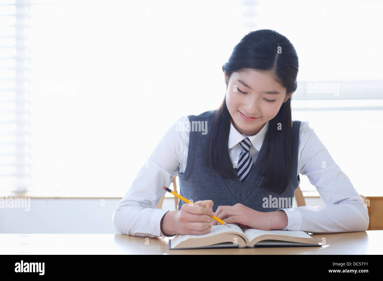 student in school uniform reading a book sitting at desk Stock Photo ...