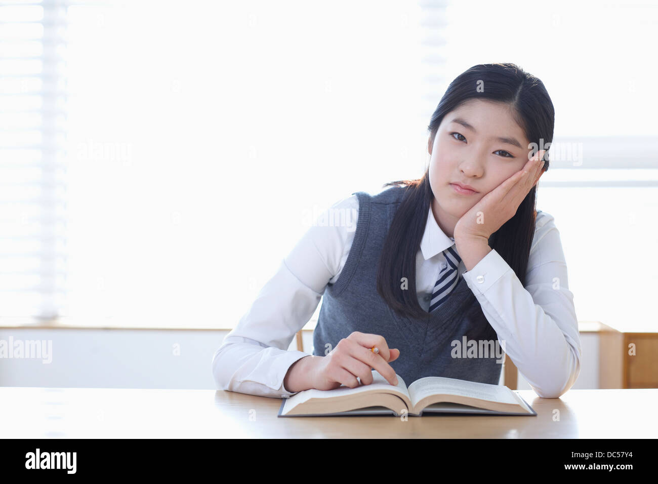 student in school uniform reading a book sitting at desk Stock Photo ...