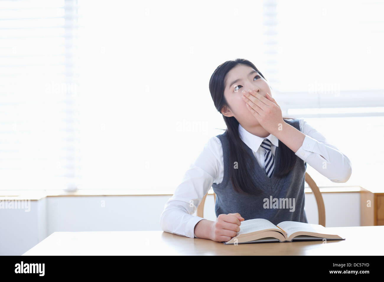 student in school uniform reading a book sitting at desk Stock Photo ...