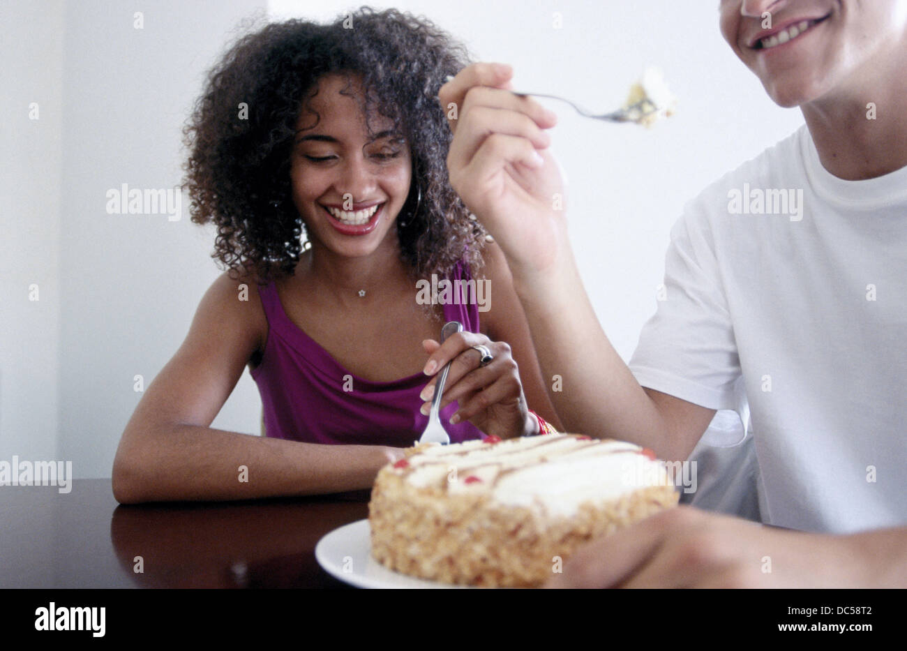 Hungry young couple eating cake with forks Stock Photo Alamy