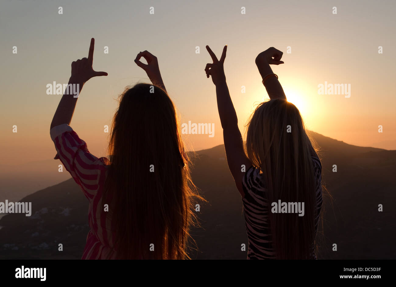 Two girls spelling the word 'Love' in the sunset Stock Photo