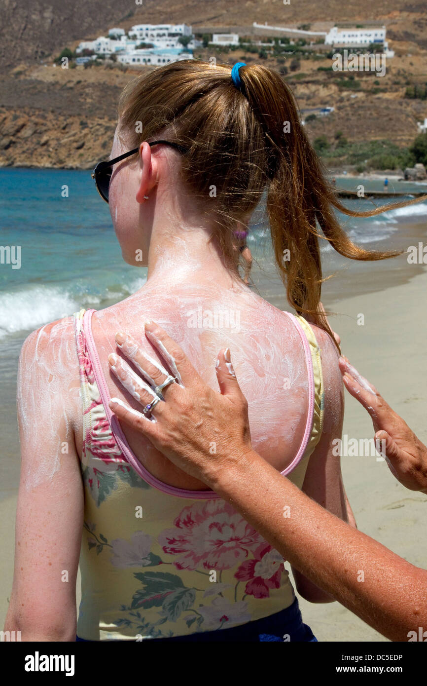 Mother puts suncream on her daughter to prevent sunburn Stock Photo
