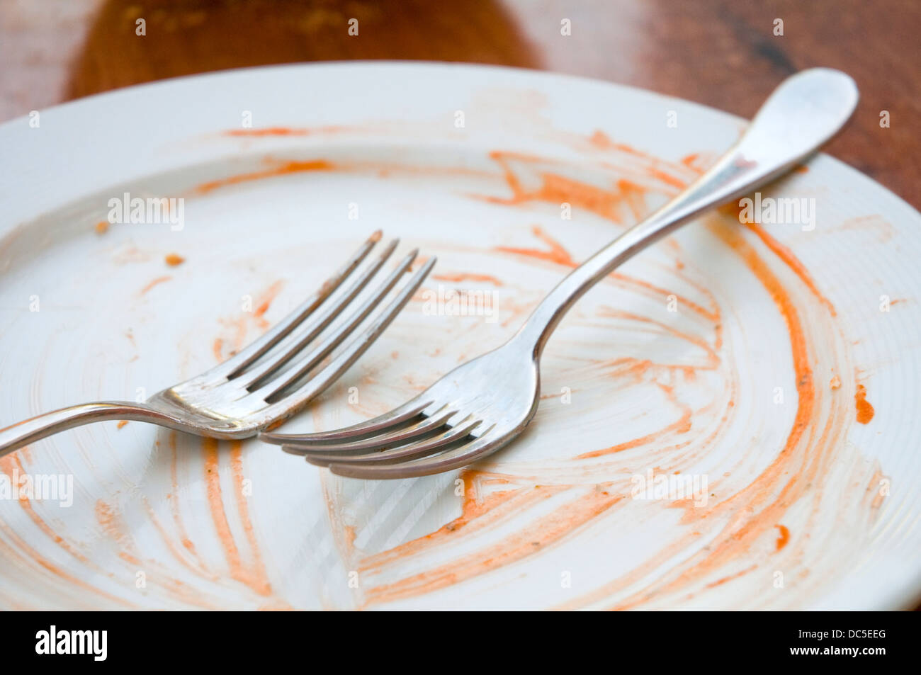Two forks on an empty plate after eating. Stock Photo
