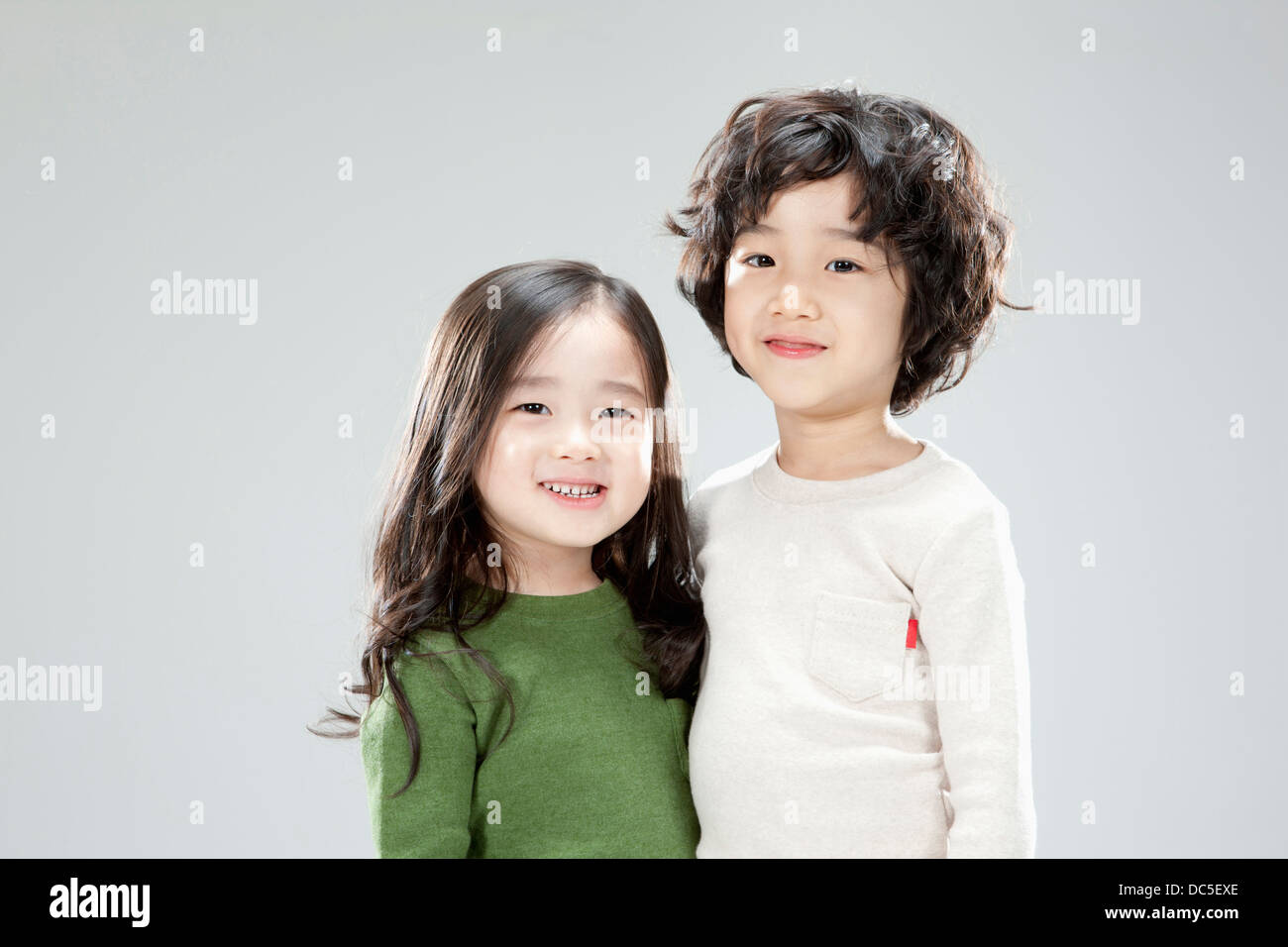 a boy and a girl standing together in grey background Stock Photo - Alamy