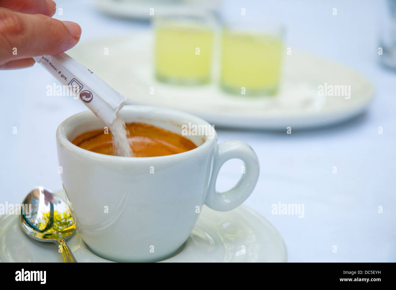 Hand pouring sugar in a cup of coffee. Close view. Stock Photo