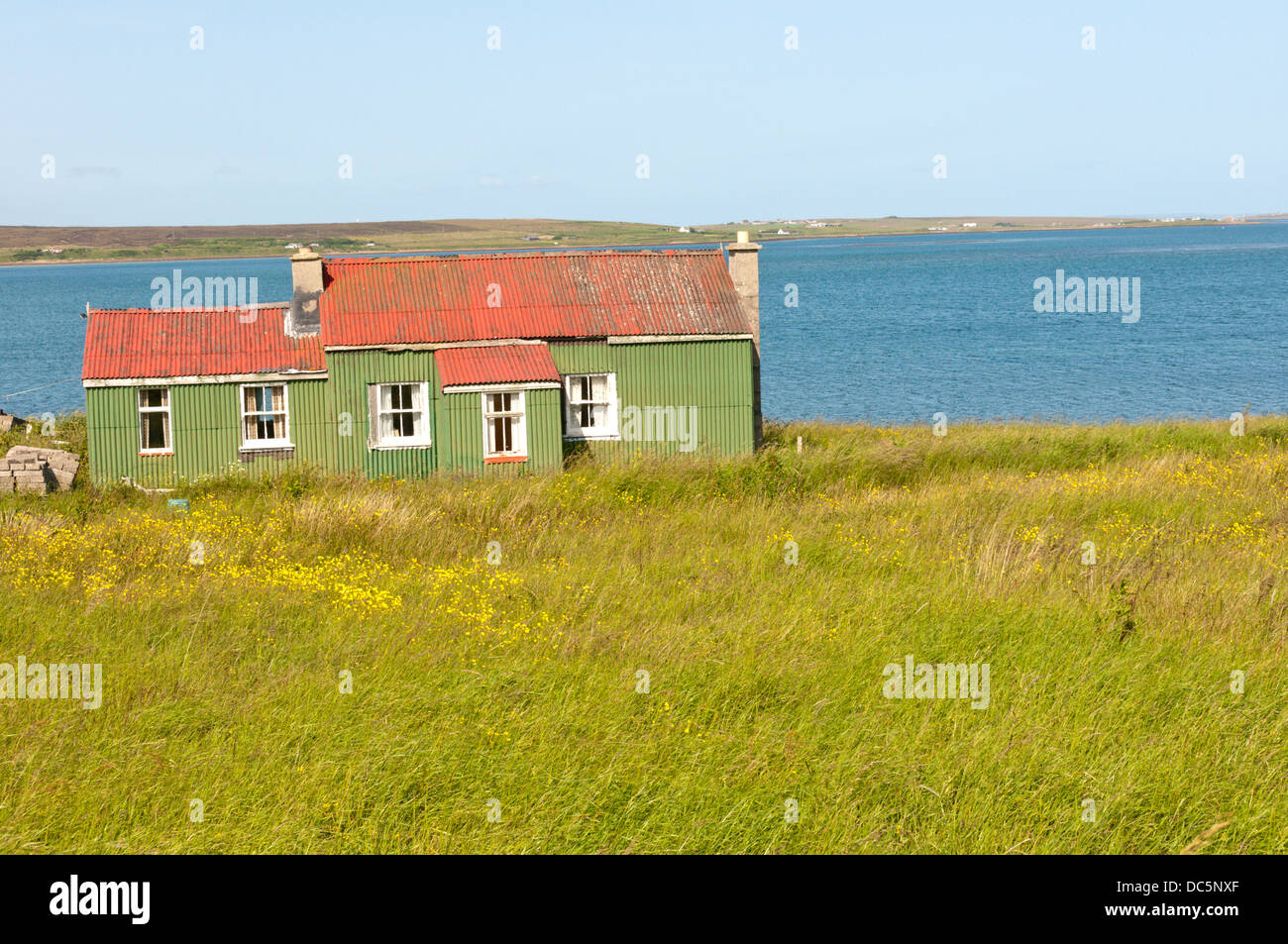 A green and red corrugated iron building overlooking North Bay on Hoy, Orkney. Stock Photo