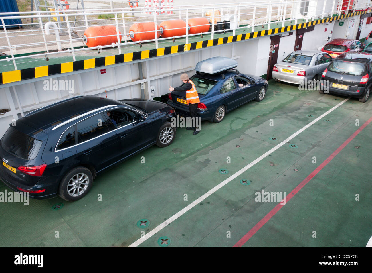 Crew member guides cars into position on the deck of the MV Hoy Head ferry between Lyness on Hoy and Stromness, Orkney. Stock Photo