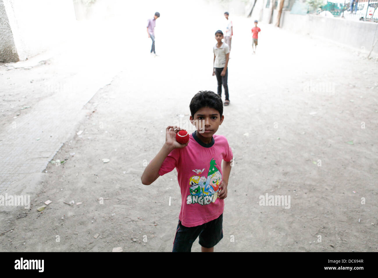 A young Indian boy shows off his cricket ball during a game of street cricket in Delhi. Stock Photo
