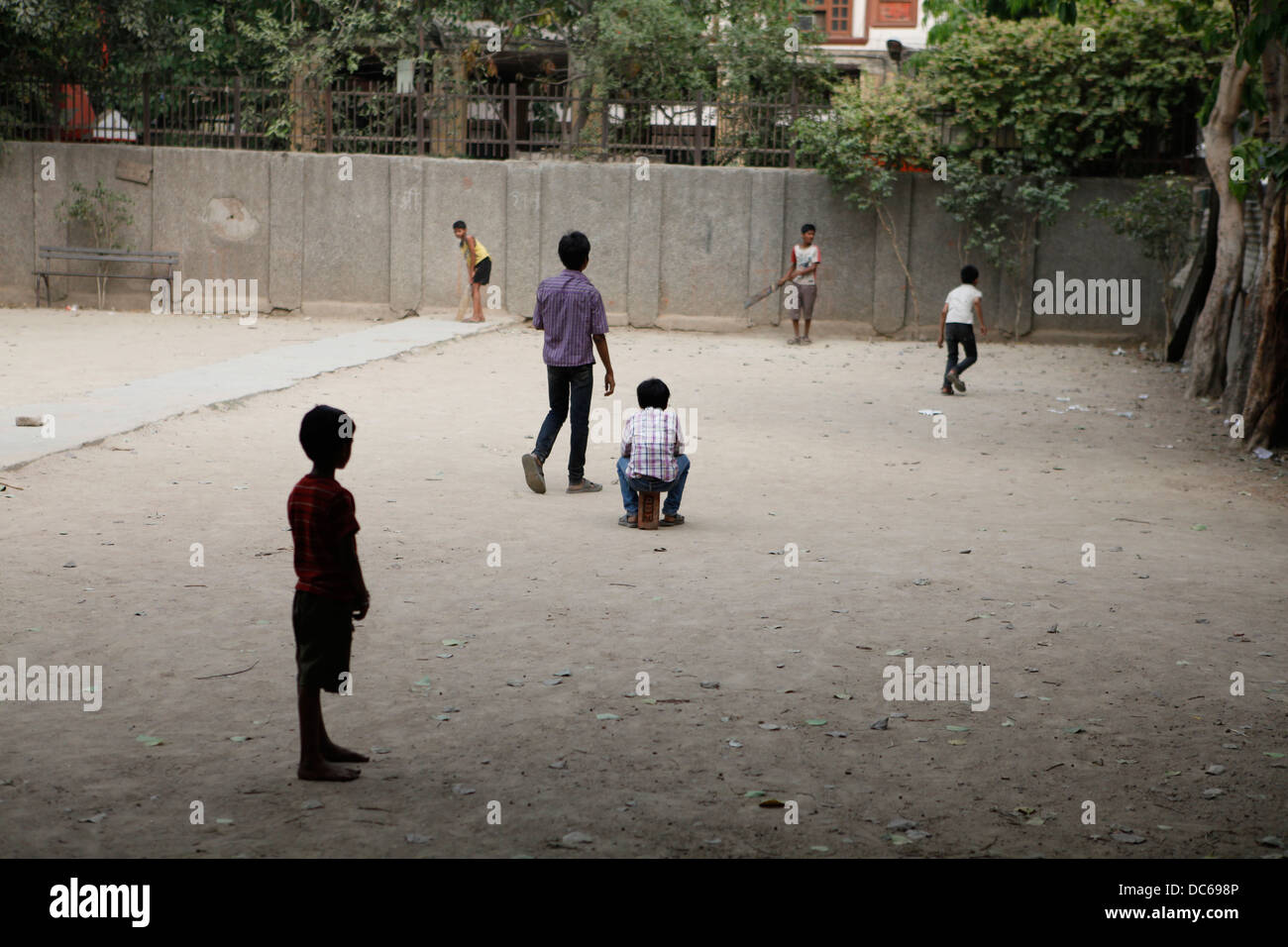 A group of young boys play street cricket on a Sunday afternoon. Stock Photo